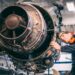 a person wearing ppe inspecting a plane engine